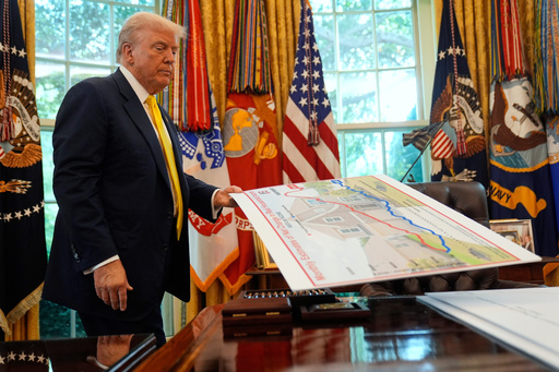 FILE - President Donald Trump holds a chart as he discusses the economy in the Oval Office of the White House, Aug. 7, 2025, in Washington. (AP Photo/Mark Schiefelbein, File)